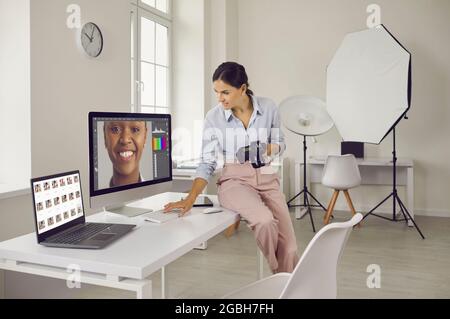 Female photographer working with female portraits at workplace with two computers in studio. Stock Photo