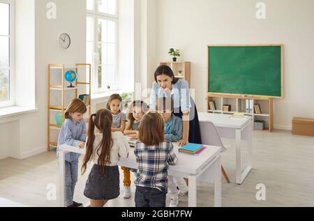 Friendly caucasian female teacher having fun to teach a lesson to children in elementary school. Stock Photo