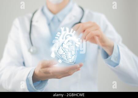 Female doctor holding virtual Heart in hand. Handrawn human organ, blurred figure,  raw photo colors. Healthcare hospital service concept stock photo Stock Photo