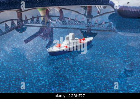 High angle shot of a plastic toy boat floating in a swimming pool Stock Photo