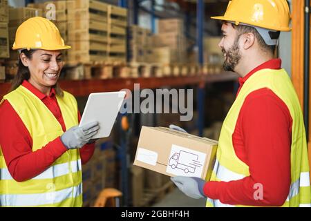 Happy workers talking while doing stock inventory inside warehouse - Focus hand holding tablet Stock Photo