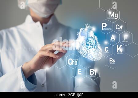 Essential nutrients for Heart health including Q10, Calcium, Magnesium, Vitamin F.Blurred portrait of doctor holding highlighted blue Heart. Stock Photo