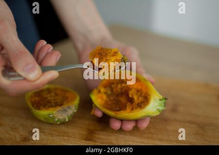 Female eats fresh organic ripe cactus pear or opuntia with a spoon. Exotic fruits, healthy eating concept Stock Photo