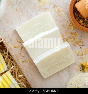 Craft artisan soap bars with herbs dried flowers. Natural bath products with dry marigold flowers for body spa skin care. Hygiene toiletries. Square Stock Photo