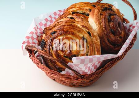 Closeup of delicious freshly baked pain aux raisins in a basket on the table Stock Photo