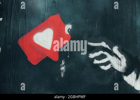 Graffiti art of an hand reaching out a heart icon in a bubble. Wall texture. Stock Photo