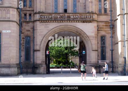Woman and children look at Whitworth Hall with a sign for the University of Manchester, Manchester, England, United Kingdom. Stock Photo