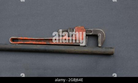 An Old Pipe Wrench and Black Iron Pipe Stock Photo
