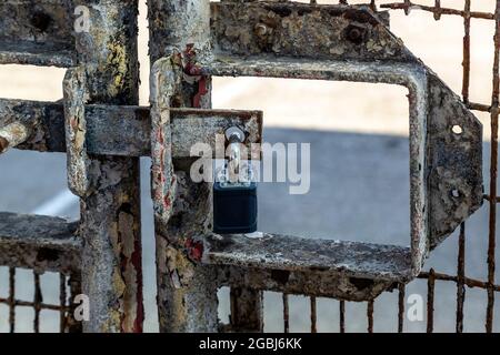 A padlock hanging on an old rusty metal gate Stock Photo