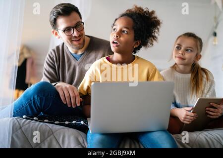 Preteen schoolgirl doing her homework with notebook at home. Child using gadgets to study. Stock Photo