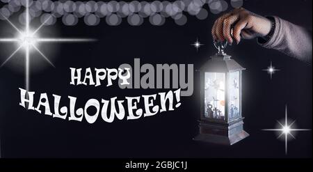 Banner Happy Halloween. A glowing lantern in a hand on a black background. Stock Photo