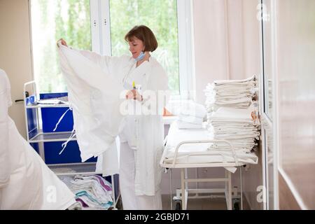 A nurse in the hospital is straightening the bed linen. Hospital attendants. Stock Photo