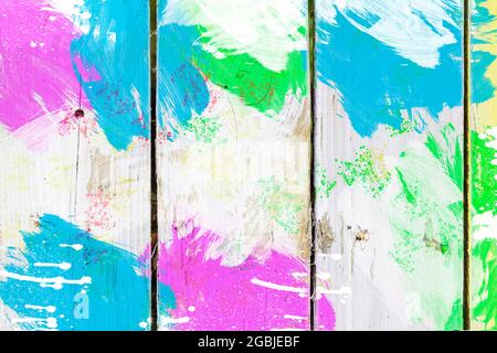 Old boards covered with bright multi-colored paints. Cheerful wooden background of bright fence. Stock Photo