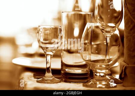 Glass goblets on the restaurant table tinted in brown. Stock Photo