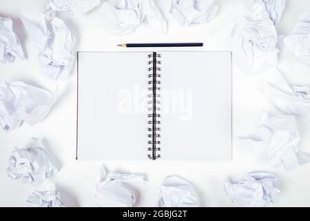 Mockup open blank notebook among crumpled sheets of paper on white table, top view. Stock Photo