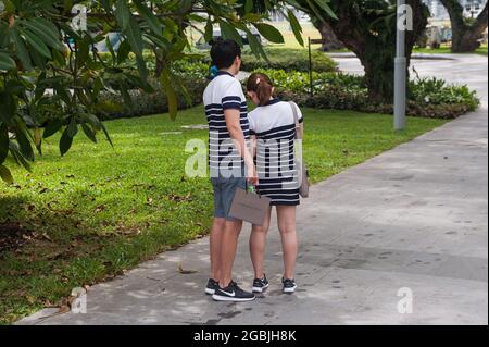 10.02.2018, Singapore, Republic of Singapore, Asia - A young couple wearing fashionable matching clothes is seen standing in a park in the city centre. Stock Photo