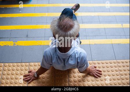 19.07.2018, Singapore, Republic of Singapore, Asia - An elderly man with a grey fringe of hair sits on the steps of a staircase in Chinatown. Stock Photo