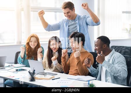 Group of international people using laptop and shaking clenched fists Stock Photo