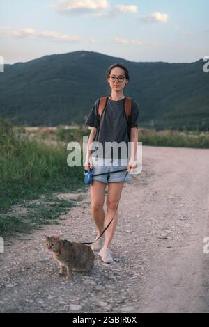 Woman walking with a cat on background of mountain ridge. Stock Photo