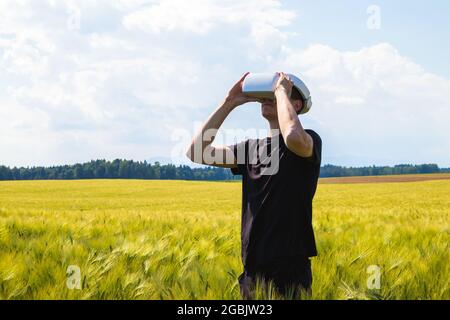 Man using virtual reality glasses outside in nature on a wheat farming field. Stock Photo