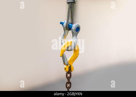 Close up of yellow machine industrial crane hook isolated on background. Coupling. Safety chain and carbine. Stock Photo