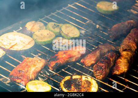 Grilling meat rolls called mici or mititei with vegetables Stock Photo