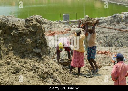 Howrah, West Bengal, India - 7th May 2017 : Indian male workers digging and carrying out soil at buliding construction site. India has a huge populati Stock Photo