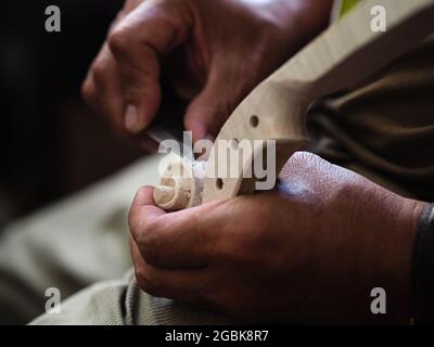 Luthier working on violin head and curl Stock Photo