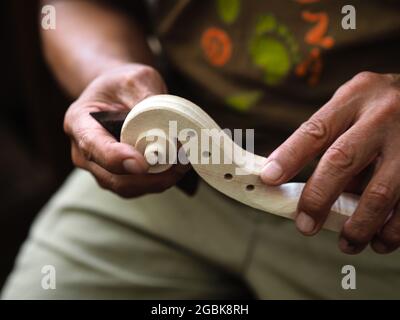 Luthier working on violin head and curl Stock Photo