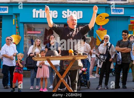 Edinburgh, Scotland, UK. 4th August  2021.  Edinburgh City Centre and Old Town busy this afternoon in warm sunny weather. Pic; Street performer drew big crowd during his magic trick show on the Royal Mile.  Iain Masterton/Alamy Live news. Stock Photo