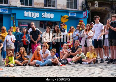 Edinburgh, Scotland, UK. 4th August  2021.  Edinburgh City Centre and Old Town busy this afternoon in warm sunny weather. Pic; Audience watch street performer during show on the Royal Mile.  Iain Masterton/Alamy Live news. Stock Photo
