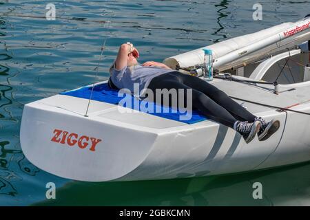 cowes week, isle of wight, female crew member, yachtswoman on boat, yachtswoman resting during postponement, lady lying on boat, yachting regatta, Stock Photo