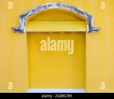The old concrete vent on the ach of the yellow wall, old church in the European style in the Thai temple, front view for the background. Stock Photo
