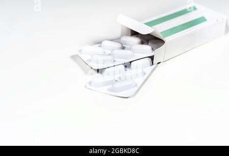 White blister with pills in a green and white box isolated on a white background. Chemistry and medicine. Healthcare and cure concept. Stock Photo