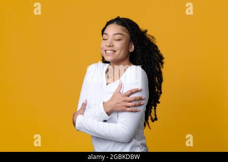 Love Yourself Concept. Happy Young African American Lady Embracing Herself Stock Photo