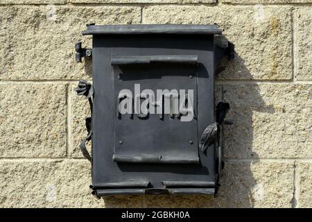 A black metal mailbox hangs on the wall of the house. Russian word: mail. Stock Photo