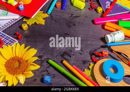 School supplies on a black chalkboard background. Pencils, paints, scissors, and colored notebooks. Back to school concept, copy space Stock Photo