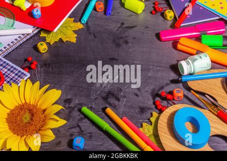 School supplies on a black chalkboard background. Pencils, paints, scissors, and colored notebooks. Back to school concept, copy space Stock Photo