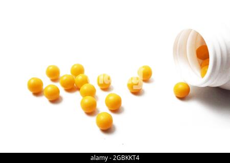 vitamin pills are scattered on a white background near a jar of vitamins,
