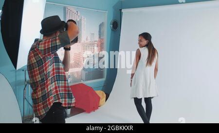 Backstage of photo shoot: multiracial young woman posing for fashion magazine photo shoot. There is white background behind the model. Stock Photo