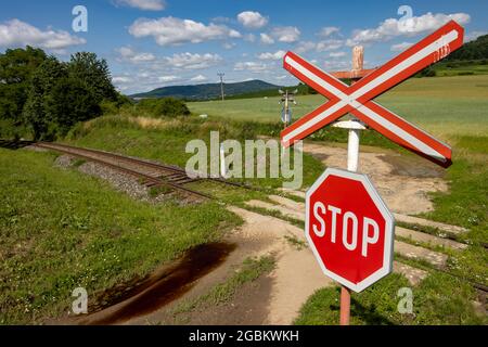 A red STOP sign before crossing the tracks. Stock Photo