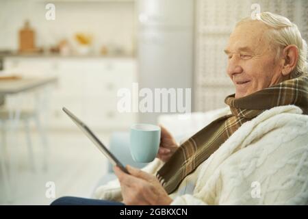 Smiling male pensioner using tablet to communicate with doctor Stock Photo