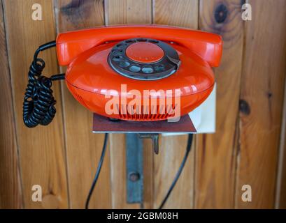 Old retro dial telephone in orange colour on wooden background Stock Photo