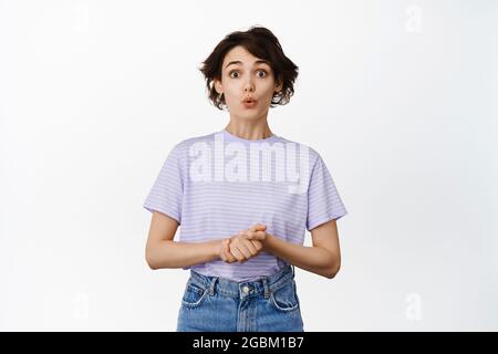 Image of hopeful brunette girl, look surprised with puckered lips, wow face, hold hands together, waiting for results, expecting, anticipating smth Stock Photo