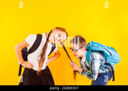 The cute little schoolboy pulls the schoolgirl's braid Stock Photo