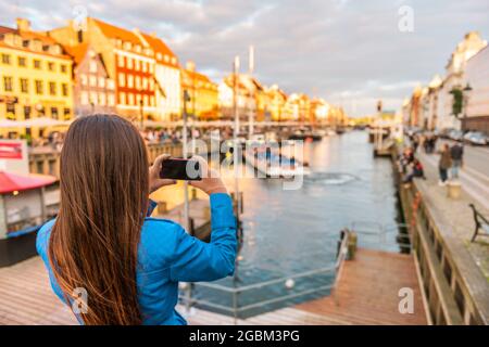 Copenhagen Denmark travel tourist woman taking photo of Nyhavn water canal old town famous tourism destination, attraction in scandinavia, Europe Stock Photo