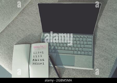 Cyber security. Easy passwords weak security online protection on the web. Laptop computer with handwritten passwords in book Stock Photo