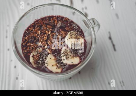 Acai smoothie breakfast bowl with fresh sliced bananas topping on frozen berries shake. Healthy organic breakfast top view at home Stock Photo