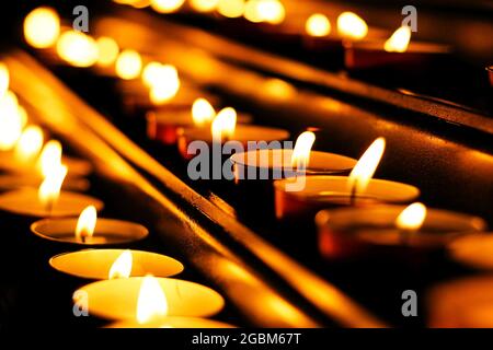 lit candles in row, detail of church petitions area, light up the dark Stock Photo