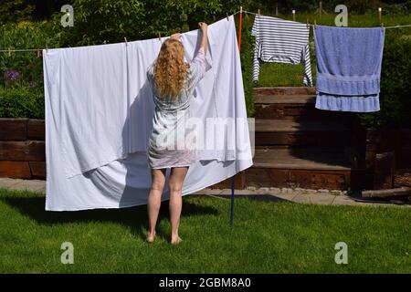 Long haired lady is hanging washing on a sunny day. Stock Photo